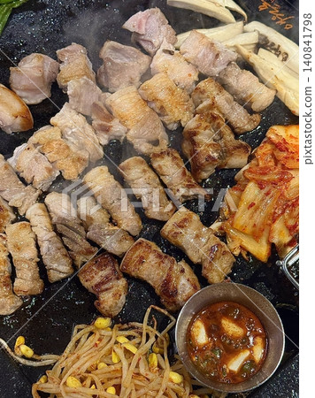 Grilled samgyeopsal, showcasing thick slices of pork belly sizzling on the grill. A popular Korean barbecue dish, capturing the essence of a delicious dining experience. Grilled samgyeopsal, showcasing thick slices of pork belly sizzling on the grill. A popular Korean barbecue dish, capturing the essence of a delicious dining experience. 140841798