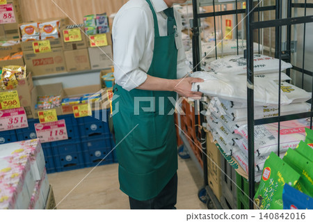 A male store clerk replenishing rice bags at a supermarket. A male store clerk replenishing rice bags at a supermarket. 140842016