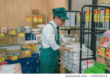 一位戴眼鏡的男員工正在超市補充米。 一位戴眼鏡的男員工正在超市補充米。 140842018