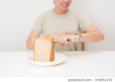Happy smiling woman with whole wheat bread and time watch. concept of intermittent fasting, IF, meal timing, and choosing healthy carbohydrates for a balanced diet and weight loss management Happy smiling woman with whole wheat bread and time watch. concept of intermittent fasting, IF, meal timing, and choosing healthy carbohydrates for a balanced diet and weight loss management 140842130