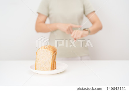 Happy smiling woman with whole wheat bread and time watch. concept of intermittent fasting, IF, meal timing, and choosing healthy carbohydrates for a balanced diet and weight loss management Happy smiling woman with whole wheat bread and time watch. concept of intermittent fasting, IF, meal timing, and choosing healthy carbohydrates for a balanced diet and weight loss management 140842131