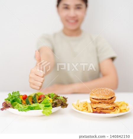 happy woman choose vegetables Salad and thumbs up gesture. Healthy and Unhealthy Food Choice, Calories and Nutrition of vegetables and Hamburger. dieting, weight loss control, junk food and lifestyle happy woman choose vegetables Salad and thumbs up gesture. Healthy and Unhealthy Food Choice, Calories and Nutrition of vegetables and Hamburger. dieting, weight loss control, junk food and lifestyle 140842150