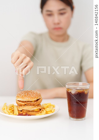 woman showing thumbs down, Rejecting and refusing with Juicy beef burger, potato chips and carbonated Soft drinks. Unhealthy, High calorie, Fast food craving, Obesity, diet, weight loss and junk food woman showing thumbs down, Rejecting and refusing with Juicy beef burger, potato chips and carbonated Soft drinks. Unhealthy, High calorie, Fast food craving, Obesity, diet, weight loss and junk food 140842156
