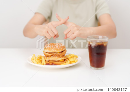 Unhappy woman showing Rejecting and refusing with Juicy beef burger, potato chips and carbonated Soft drinks. Unhealthy, High calorie, Fast food craving, Obesity, diet, weight loss and junk food Unhappy woman showing Rejecting and refusing with Juicy beef burger, potato chips and carbonated Soft drinks. Unhealthy, High calorie, Fast food craving, Obesity, diet, weight loss and junk food 140842157