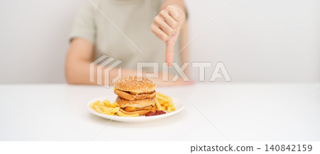 woman showing thumbs down, Rejecting and refusing with Juicy beef burger, potato chips and carbonated Soft drinks. Unhealthy, High calorie, Fast food craving, Obesity, diet, weight loss and junk food 140842159