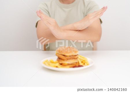 Unhappy woman showing Rejecting and refusing with Juicy beef burger, potato chips and carbonated Soft drinks. Unhealthy, High calorie, Fast food craving, Obesity, diet, weight loss and junk food Unhappy woman showing Rejecting and refusing with Juicy beef burger, potato chips and carbonated Soft drinks. Unhealthy, High calorie, Fast food craving, Obesity, diet, weight loss and junk food 140842160