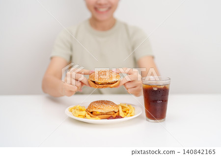 woman eating Juicy beef burger with melted cheddar cheese, potato chips and carbonated Soft drinks. Unhealthy, High calorie, Fast food craving, Obesity, diet, weight loss, junk food and lifestyle woman eating Juicy beef burger with melted cheddar cheese, potato chips and carbonated Soft drinks. Unhealthy, High calorie, Fast food craving, Obesity, diet, weight loss, junk food and lifestyle 140842165