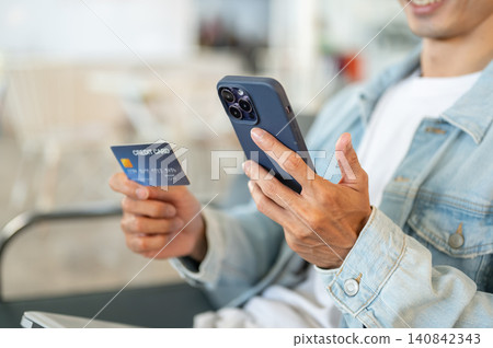Close up of a man's hands holding smartphone and credit card for mobile banking and online purchase. Close up of a man's hands holding smartphone and credit card for mobile banking and online purchase. 140842343