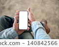 Close up of man's hands holding white screen smartphone while sitting, showcasing digital lifestyle. 140842566
