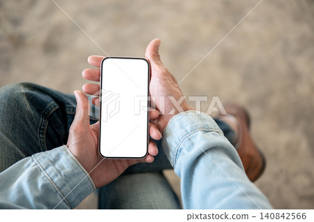 Close up of man's hands holding white screen smartphone while sitting, showcasing digital lifestyle. Close up of man's hands holding white screen smartphone while sitting, showcasing digital lifestyle. 140842566