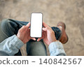Close up of white smartphone screen held with both hands for app, website and interface presentation 140842567