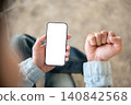Close up of hands holding white screen phone while making a fist, ready for app or web customization 140842568