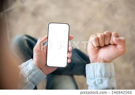 Close up of hands holding white screen phone while making a fist, ready for app or web customization Close up of hands holding white screen phone while making a fist, ready for app or web customization 140842568