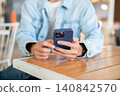 Close up of a man's hands using smartphone at cafe table, browsing online content in relaxed setting 140842570