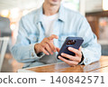 Close up of man's hand interacting with smartphone sitting at cafe table showcasing digital lifestyle 140842571