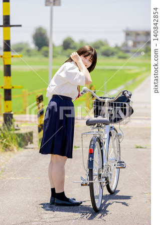 A summer scene of high school girls on their way to school, smiling in front of a railroad crossing with their bicycles. A summer scene of high school girls on their way to school, smiling in front of a railroad crossing with their bicycles. 140842854