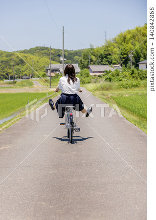 一位高中女生騎著腳踏車沿著鄉村小路回家,這是她的背影。 一位高中女生騎著腳踏車沿著鄉村小路回家,這是她的背影。 140842868