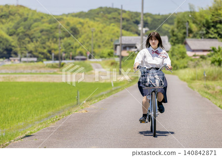 一名高中女生騎著腳踏車沿著鄉村小路去上學。 一名高中女生騎著腳踏車沿著鄉村小路去上學。 140842871