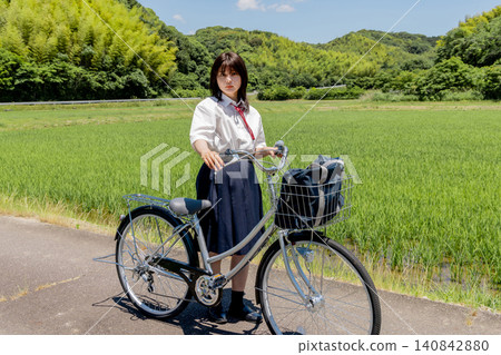 Portrait of a high school girl cycling to school amidst a rural landscape. 140842880