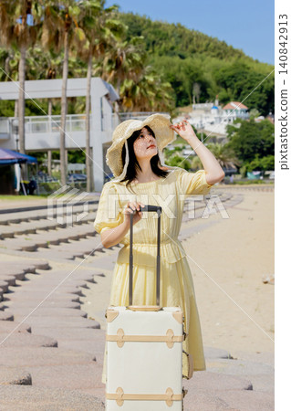 A young woman enjoying her trip at a resort, wearing a straw hat and carrying a suitcase. A young woman enjoying her trip at a resort, wearing a straw hat and carrying a suitcase. 140842913