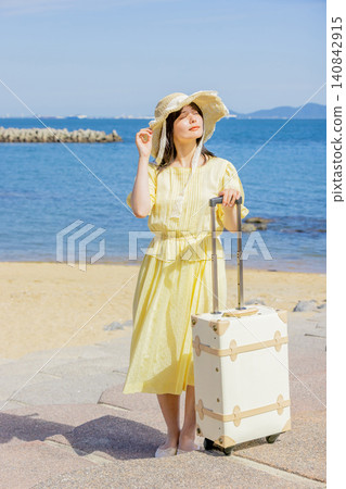 A young woman enjoying the summer at a seaside resort with her suitcase. A young woman enjoying the summer at a seaside resort with her suitcase. 140842915