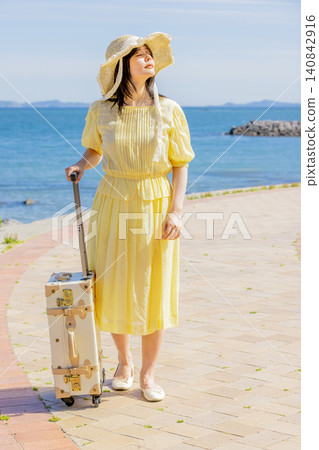 A young woman enjoying the summer at a seaside resort with her suitcase. A young woman enjoying the summer at a seaside resort with her suitcase. 140842916