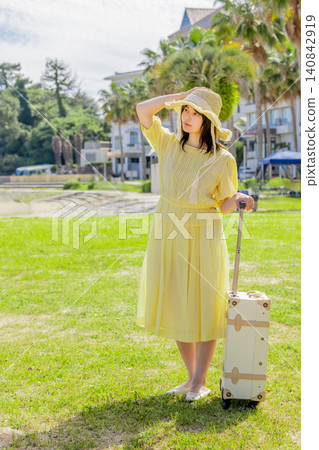 A young woman with a suitcase enjoying a summer trip in front of a resort hotel. A young woman with a suitcase enjoying a summer trip in front of a resort hotel. 140842919