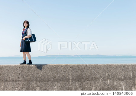 A high school girl standing on a seawall and a copy space of the blue sky. 140843006