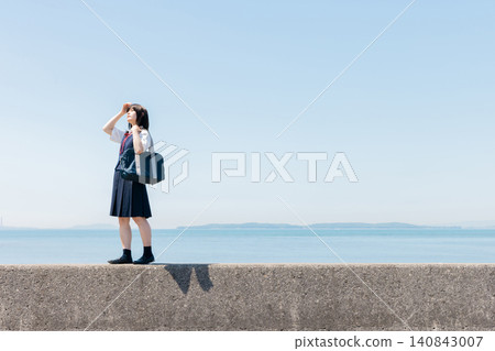 一名高中女生站在海堤上,背景是一片藍天。 一名高中女生站在海堤上,背景是一片藍天。 140843007