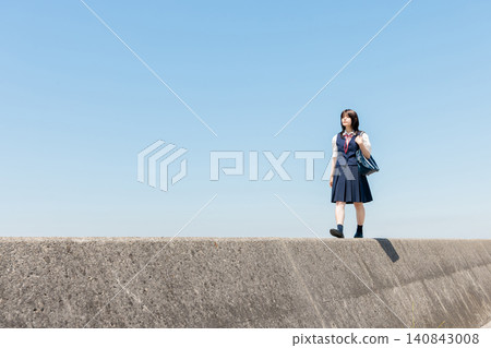 一位高中女生在藍天下沿著防波堤行走,留白逐漸展開。 一位高中女生在藍天下沿著防波堤行走,留白逐漸展開。 140843008