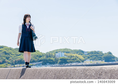 夏日藍天下,一名高中女生沿著海邊的防波堤散步。 夏日藍天下,一名高中女生沿著海邊的防波堤散步。 140843009