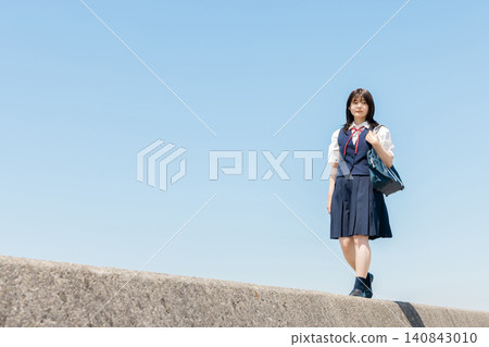 一位高中女生在藍天下沿著防波堤行走,留白逐漸展開。 一位高中女生在藍天下沿著防波堤行走,留白逐漸展開。 140843010
