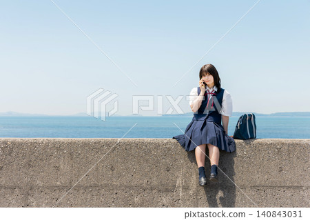 A high school girl talking on her smartphone on the beach. 140843031