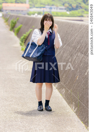 A portrait of a high school girl smiling on her way to school by the sea. 140843049