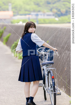 A high school girl on her bicycle turns around and smiles. A high school girl on her bicycle turns around and smiles. 140843051