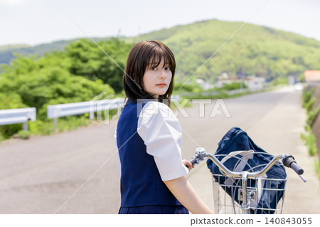 A high school girl on her bicycle turns around and smiles. A high school girl on her bicycle turns around and smiles. 140843055