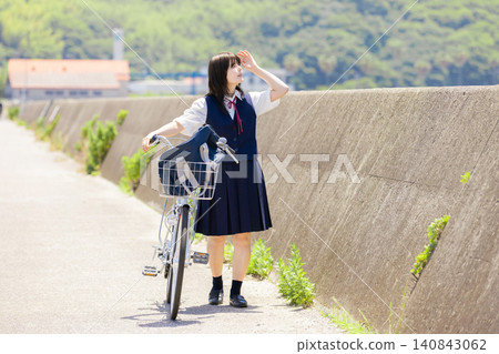 一位高中女生推著自行車走在海邊學校路上的肖像。 一位高中女生推著自行車走在海邊學校路上的肖像。 140843062