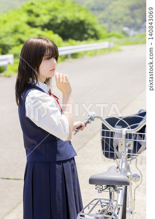 A high school girl stops while cycling to school and gazes into the distance. A high school girl stops while cycling to school and gazes into the distance. 140843069