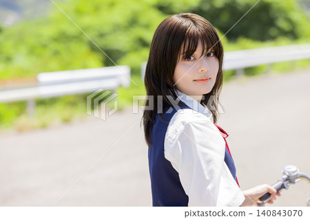 一名騎著腳踏車的高中女生轉過身來，露出微笑。 140843070