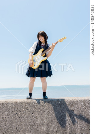 A high school girl playing an electric guitar on the beach. A high school girl playing an electric guitar on the beach. 140843085