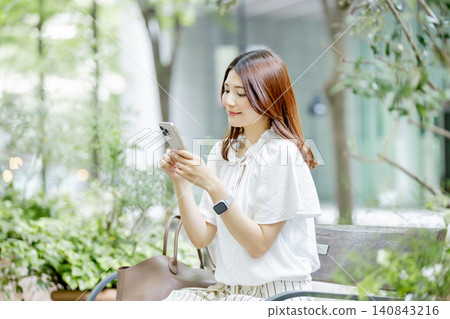 一位日本女子在長椅上使用智慧型手機 一位日本女子在長椅上使用智慧型手機 140843216
