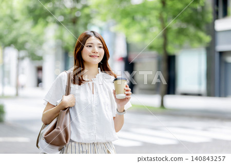 A Japanese woman enjoying a relaxing moment with a takeaway coffee. A Japanese woman enjoying a relaxing moment with a takeaway coffee. 140843257