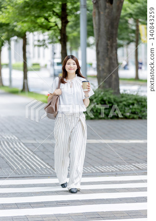 一位日本女子手持一杯咖啡,走過辦公區。 一位日本女子手持一杯咖啡,走過辦公區。 140843259