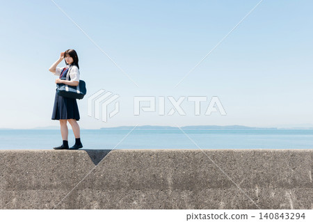 一名高中女生站在海堤上，背景是一片藍天。 140843294
