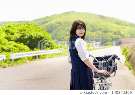 一名騎著腳踏車的高中女生轉過身來,露出微笑。 一名騎著腳踏車的高中女生轉過身來,露出微笑。 140843309