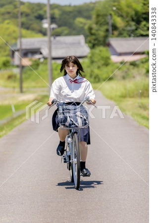 一名高中女生騎著腳踏車沿著鄉村小路去上學。 一名高中女生騎著腳踏車沿著鄉村小路去上學。 140843338
