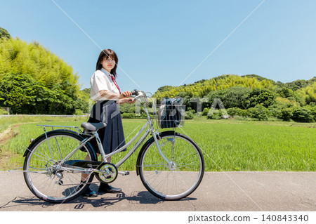 A high school girl on her bicycle, on her way to school, in a rural landscape. A high school girl on her bicycle, on her way to school, in a rural landscape. 140843340