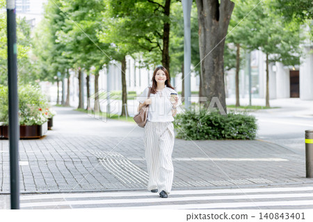 一位日本女子手持一杯咖啡，走過辦公區。 140843401