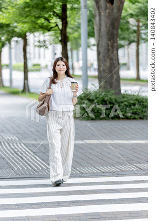 一位日本女子手持一杯咖啡,走過辦公區。 一位日本女子手持一杯咖啡,走過辦公區。 140843402