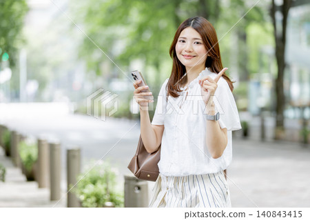 一位日本女性正在用智慧型手機指路。 一位日本女性正在用智慧型手機指路。 140843415